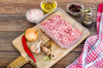 Raw minced meat with spices for cooking on wooden board