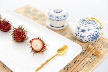 Elegant rambutan asian desert with chinaware, golden spoon and chopstick.