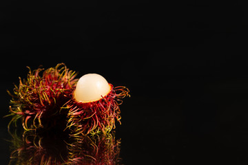 Rambutan on a mirror surface with a black background