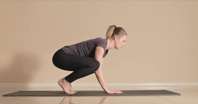Yoga fail as a young female instructor attempts the crane or crow pose and falls down and laughs then her class throws pillows at her jokingly from off screen
