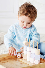 Child boy playing in his room with a wooden toy sorter