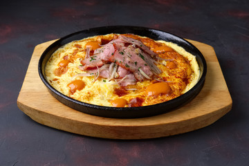 Omelette with bacon and fried onion on cast-iron pan