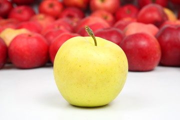 Yellow Apple on a background of red apples on white background