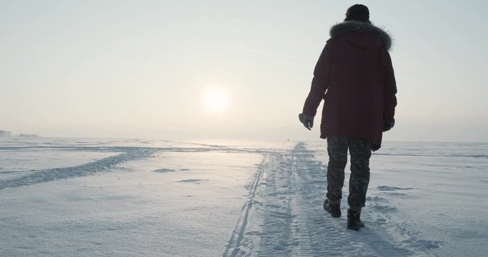 Young traveller goes through a blizzard at beautiful sunset. Polar expedition
