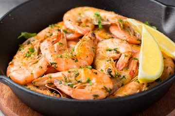 Fried shrimps in shell with parsley, coriander, garlic and oil in pan. Delicious Mediterranean cuisine, vegetarian food, healthy protein