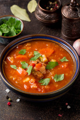 Thick tomato soup with meat, cereals and vegetables. Traditional Oriental cuisine, spicy stew with beef or lamb, rice and spices. Food on dark background