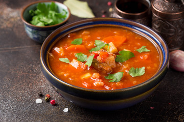 Thick tomato soup with meat, cereals and vegetables. Traditional Oriental cuisine, spicy stew with beef or lamb, rice and spices. Food on dark background