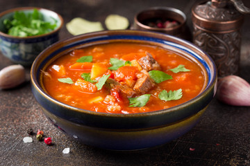 Thick tomato soup with meat, cereals and vegetables. Traditional Oriental cuisine, spicy stew with beef or lamb, rice and spices. Food on dark background