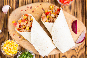 Burrito in tartilla with meat, vegetables, white beans, red pepper, corn. Delicious lunch, Mexican food, homemade snack
