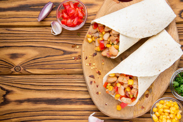 Burrito in tartilla with meat, vegetables, white beans, red pepper, corn. Delicious lunch, Mexican food, homemade snack