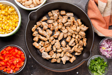 Preparation of filling for burritos in tortillas with meat, vegetables, white beans, red pepper, corn. Delicious lunch, Mexican food, homemade snack