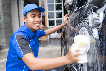 male car cleaning service worker washing black car