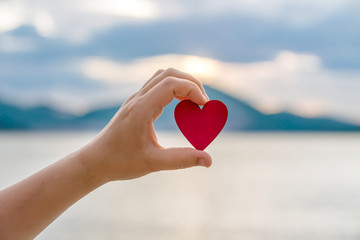 Fototapeta premium Girl holding a symbol of love over the sea 