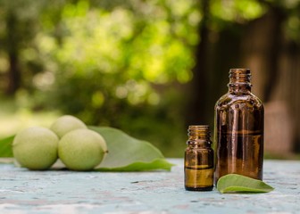 Walnut oil in a bottle and green nuts. Selective focus