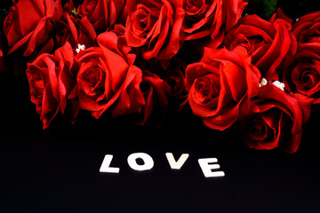 Wooden letters word "LOVE" and red rose on black background