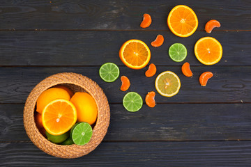 Bowl of citrus fruits on black wooden background, top view
