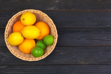 Bowl of citrus fruits on black wooden background, top view
