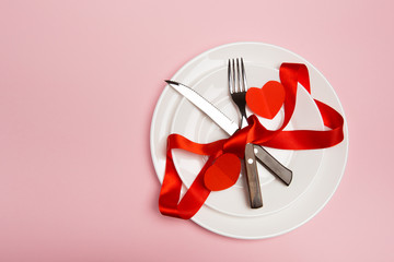 Festive table setting for Valentine's Day with fork, knife,  hearts on a red background. Top view. - Image.