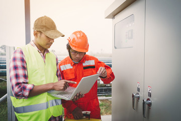 engineer or electrician holding laptop for inspect and checking main distribution board by wifi technology ;smart technology for operation of solar power plant by smart operator