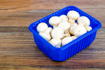 Fresh white champignons in blue plastic packaging