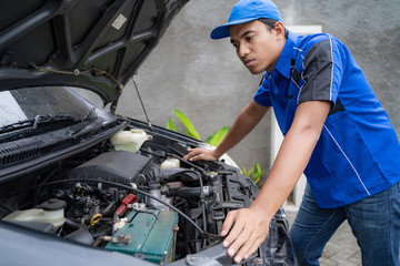 blue uniform car engineer worker looking into car's engine