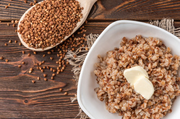 Buckwheat porridge with butter on dark wooden background.