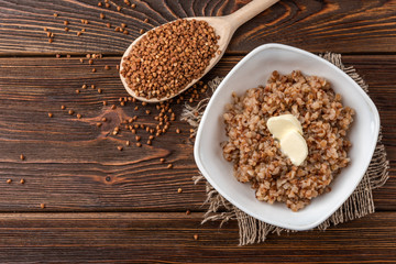 Buckwheat porridge with butter on dark wooden background.