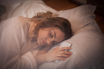 Woman alseep next to smart phone .