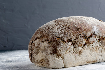 Closeup of one delicious crispy rye bread on flour against grey wall