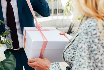 Female hands holding beautiful big gift wrapped with satin ribbon