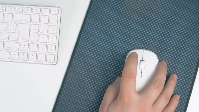 Man working in office and clicking on white computer mouse. 4K close up footage.
