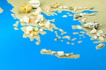 Contours of Greece and islands. The map is made of sand, with seashells on top.