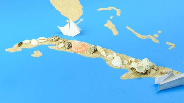 Paper boats off the coast of Cuba. The map is lined with sand, with shells on top.