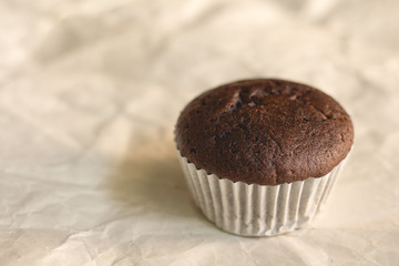 Chocolate cupcake on brown crumpled paper with copy space.