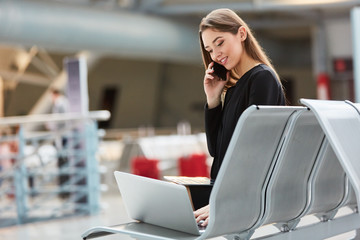 Frau auf Geschäftsreise mit Laptop und Smartphone