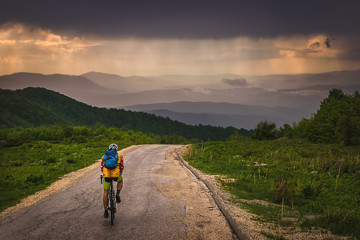 Man cycling in mountain on a rainy day. Stunning view on mountain range from Stara Planina mountain in Serbia. 