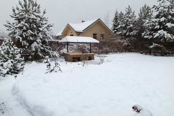 Backyard Patio.Landscape  with barbeque area, snowbanks of white snow, pine trees in country garden. Country life concept.