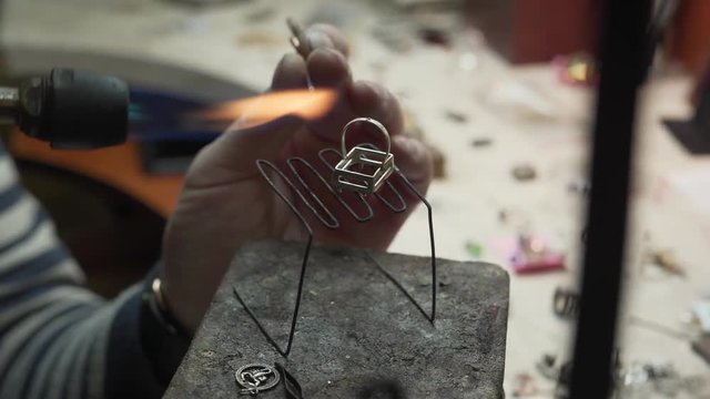 Male strong hands heating the steel/iron stick and solder the big glod ring with the help of it. Jewelry making/producing concept