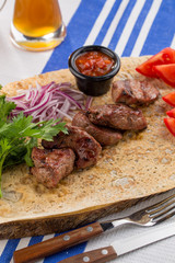 Fresh, homecooked on the grill fire meat beef shish kebab with vegetables with barbecue sauce on textile background