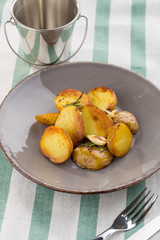 Baked unpeeled potatoes on grey plate on textile background