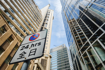 No Parking 24 hours Sign with chinese language surrounded by tall buildings in Hong Kong's business district.