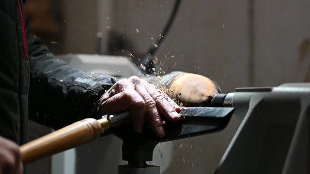 wood working man cuts piece of wood to bowl on turnery machine