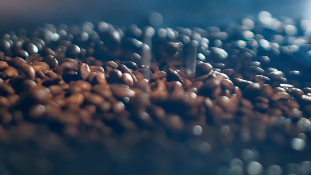 Close-up slowmo video of brown coffee beans falling down on a pile of beans