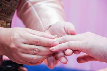 The man wears a wedding ring on woman's hand
