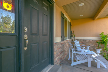 Green front door and porch with white chairs