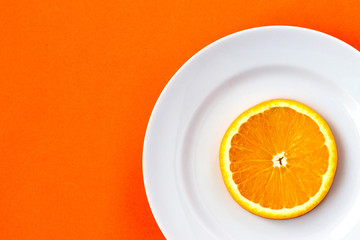 Top view of a plate with sliced orange on an orange background.