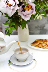 tea and pancakes on the background of beautiful pions.