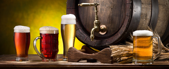 Glasses of beer and beer cask on the wooden table. Craft brewery.
