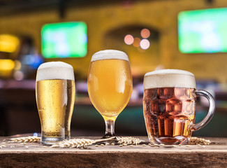 Glasses of beer on the wooden table. Blurred pub interior at the background.