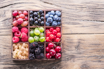 Colorful berries in wooden box on the table. Top view.